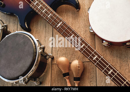 Pendant la répétition en studio. Vue du dessus de l'ensemble des instruments de musique : guitare électrique, batterie, tambourin et maracas d'or couché sur fond de bois. Instruments de musique. Des équipements de musique Banque D'Images