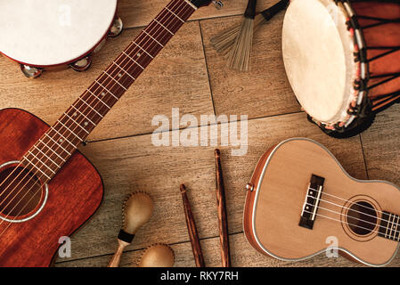 Instruments de musique ethnique set : tambourin, tambour en bois, pinceaux, bâtons de bois, maracas et guitares portant sur plancher en bois. Music concept. Instruments de musique. Banque D'Images