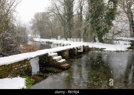 Pont battant pierre traversant la rivière Leach à Eastleach Turville tôt le matin de la neige. Eastleach Turville, Cotswolds, Gloucestershire, Royaume-Uni Banque D'Images