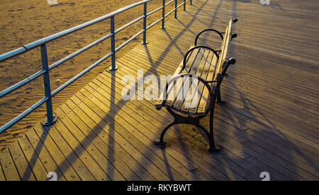 Banc sur la promenade au printemps au coucher du soleil Banque D'Images