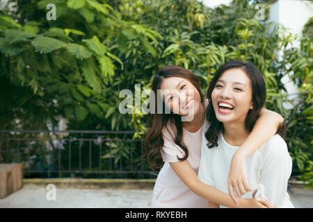 Les beautés dans le style. Deux belles jeunes femmes bien habillés smiling at camera while standing embracing outdoors Banque D'Images