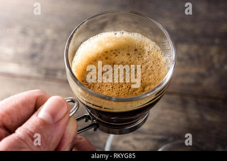 Homme tenant un café chaud, le verre sur la table en bois.Close up Banque D'Images