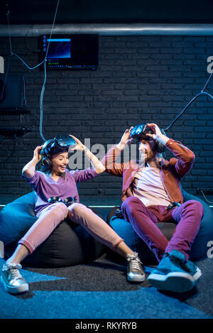 L'homme et de la femme avec des émotions excités assis ensemble après le jeu en réalité virtuelle dans la salle de jeu Banque D'Images