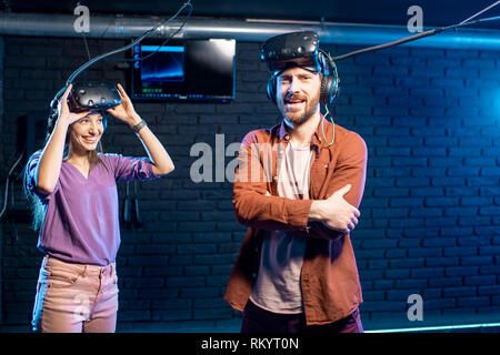 Homme heureux gagner jeu de réalité virtuelle avec Jeune femme debout dans la salle de jeu Banque D'Images