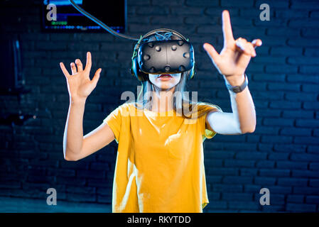 Femme de toucher l'espace de réalité virtuelle à l'aide de casque VR dans la salle de jeu Banque D'Images