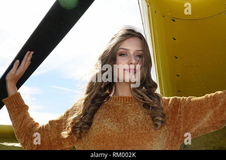 Beautiful country girl avec longs cheveux vêtue de jeans et un chandail posés avec épandage airplane Banque D'Images