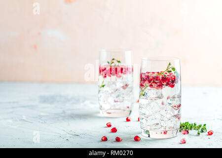 Boissons de fête, gin tonic cocktail de grenade ou de l'eau avec de la glace. detox Focus sélectif, l'espace de copie de texte, de la surface de la table en béton gris clair. Banque D'Images