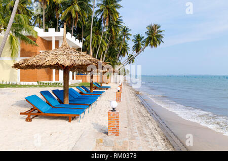 Chaises longues sous des parasols au bord de l'eau au Vietnam Banque D'Images