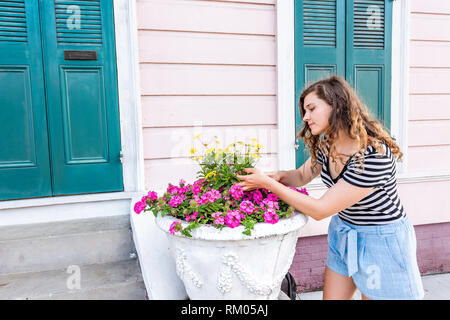 Jeune femme hipster jardinage à La Nouvelle-Orléans par jour au cours de l'architecture porte de couleur jaune et rose avec des fleurs au printemps et l'été de toucher Banque D'Images