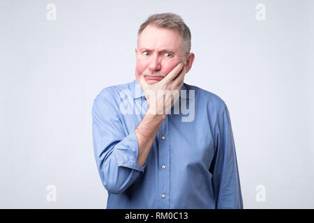 Senior man in blue shirt penser à sa pension Banque D'Images