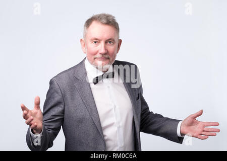 Senior business man studio isolés sur les mains de côté mur gris Banque D'Images