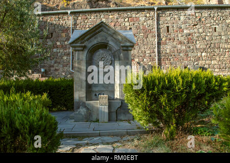 Guéghard, l'Arménie, le 20 octobre 2018 : Le monument est une source d'eau, taillée dans le basalte, dans un parc près d'un mur de pierre situé autour de Gherart Monaster Banque D'Images