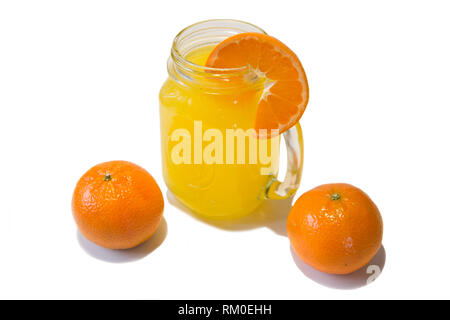 Verre de jus d'orange avec une tranche d'orange fraîche dans le haut dans un quartier branché de Kilner avec une poignée de verre Jar Banque D'Images