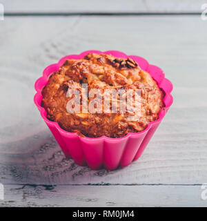 Gruau cuit dans un moule à muffins en silicone rose sur fond de cuisson en bois clair. Banque D'Images