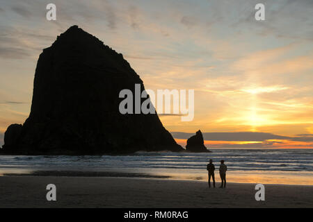 Couple en train de marcher au coucher du soleil, Cannon Beach, Oregon Banque D'Images