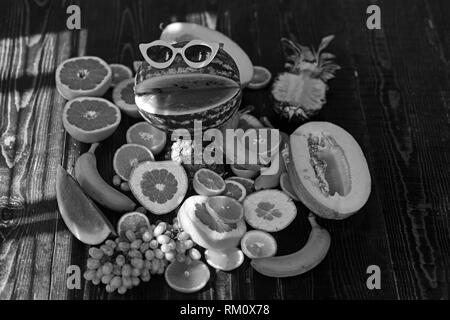 Les fruits nature morte sur table en bois. Watermelon dans Drôle de lunettes avec sourire. La nourriture végétarienne pour detox alimentation et santé. Suivre un régime vitamine et Banque D'Images