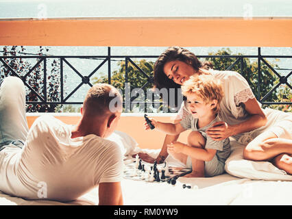 Young Beautiful woman smiling au garçon qui jouait aux échecs avec son père. Banque D'Images