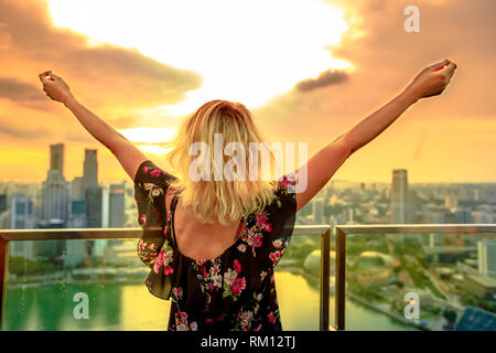 Femme blonde sans souci à la panorama à partir de toit dans le sud Marina, Singapour. Vue aérienne de la ville de la ville au coucher du soleil. Tourisme à vie Banque D'Images