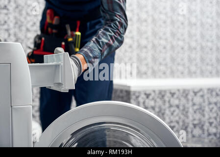 Inspection détaillée. L'homme travail plombier dans la salle de bains la vérification du travail d'wacher mashine près de tool box Banque D'Images