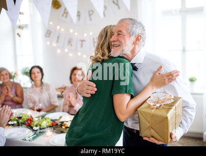 Jeune femme offrir un cadeau à son grand-père sur la partie intérieure, serrant. Banque D'Images