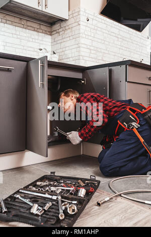 Cas d'outils. Seniour handyman réparation lavabo à la cuisine avec équipement professionnel Banque D'Images