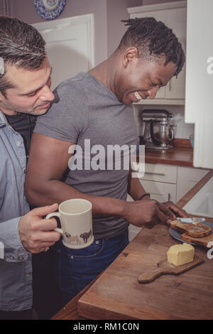 Un couple gay, partage les histoires de leur journée au travail sur une tranche de pain grillé et une tasse de thé et café dans la soirée. Banque D'Images