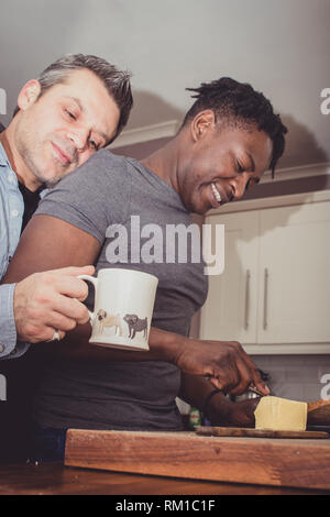 Un couple gay, partage les histoires de leur journée au travail sur une tranche de pain grillé et une tasse de thé et café dans la soirée. Banque D'Images