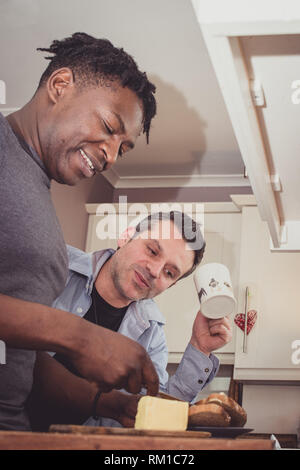 Un couple gay, partage les histoires de leur journée au travail sur une tranche de pain grillé et une tasse de thé et café dans la soirée. Banque D'Images