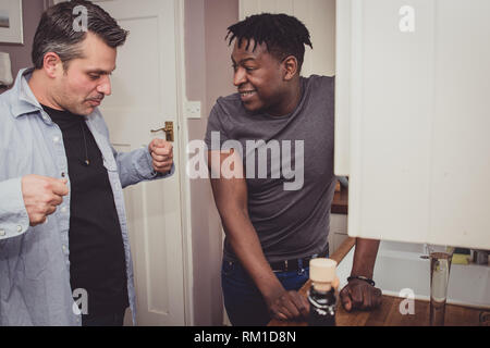 Un couple gay, partage les histoires de leur journée au travail sur une tranche de pain grillé et une tasse de thé et café dans la soirée. Banque D'Images