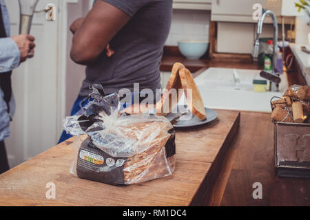 Un couple gay, partage les histoires de leur journée au travail sur une tranche de pain grillé et une tasse de thé et café dans la soirée. Banque D'Images