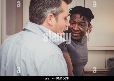 Un couple gay, partage les histoires de leur journée au travail sur une tranche de pain grillé et une tasse de thé et café dans la soirée. Banque D'Images