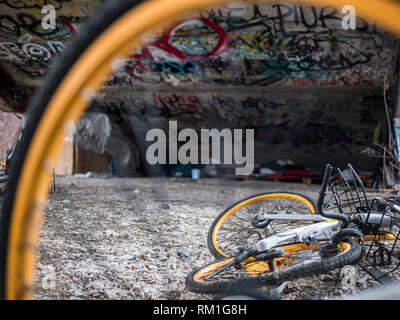 Vieille ferraille jaune des bicyclettes sous les escaliers de béton avec des graffitis et des sans-abri abri couchage Banque D'Images