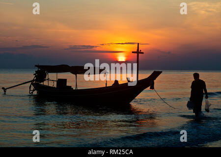 Monter dans une chaloupe au lever du soleil sur la plage de KHANOM, THAÏLANDE Banque D'Images