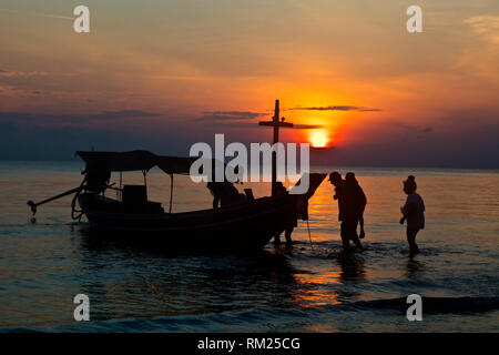 Monter dans une chaloupe au lever du soleil sur la plage de KHANOM, THAÏLANDE Banque D'Images