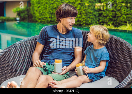 Père et fils manger le dessert avec chia seeds et de mangues à la piscine le matin. la saine alimentation, l'alimentation, les régimes végétariens et personnes concept Banque D'Images