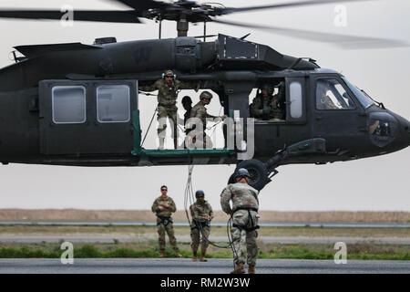 Les soldats de l'armée américaine soulever dans un UH-60 Black Hawk lors de la corde de l'insertion et l'extraction rapide de la formation du système à la zone d'atterrissage Udairi, Camp Buehring, le Koweït, le 9 février 2019. Les membres de l'équipage, affecté au 1er Bataillon, 108e Régiment d'aviation de l'armée, la Garde nationale, a mené la formation à fournir l'appui de l'aviation à un parcours du combattant. Photo a été brouillé à protéger la sécurité opérationnelle. (U.S. La Garde nationale de l'armée photo par le Sgt. Emily Finn) Banque D'Images