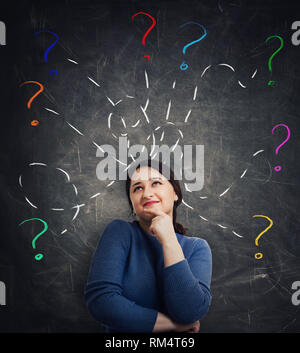 Casual young woman holding main sous le menton de la recherche des pensivement comme beaucoup de questions comme l'interrogatoire coloré dessiné autour de marques associés aux familles blackberry sur Banque D'Images