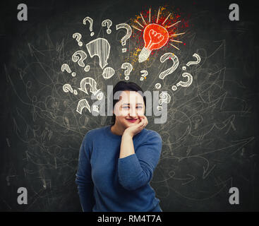 Jeune femme pensive main sous le menton, marque d'interrogatoire, ampoules et mess flèche au-dessus de la tête. Question idée et concept. Trouver une solution aux problèmes. Banque D'Images