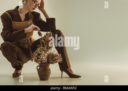 Attractive young woman holding pot en argile avec bouquet de fleurs sèches sur rond Banque D'Images