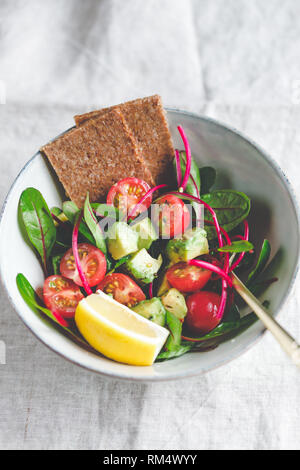 Salade saine végétarienne est faite de feuilles de blettes, tomates cerises, l'avocat, le jus de citron et l'huile d'olive dans une partie en céramique bol. Banque D'Images