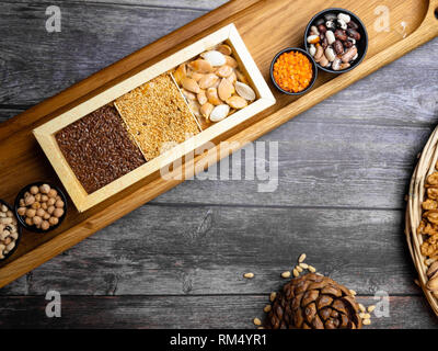 Jeu de collecte de céréales : lentilles rouges, haricots mungo, pois chiche, sarrasin, sur une table de cuisine en bois avec les graines de lin, graines de citrouille et le sésame, le cèdre Banque D'Images