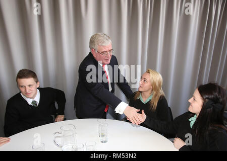 Un vice-Premier ministre irlandais Tánaiste, Eamon Gilmore salue des étudiants (de gauche à droite) Keelan Murry, Caithlin O'Neill et Carla Murray de la St Patrick, Belfast après un déjeuner-causerie marquant le 15ème anniversaire de la signature de l'Accord de Belfast, lundi 29 avril à la MAC. Le Tánaiste a rejoint le secrétaire d'État pour l'Irlande du très honorable Theresa Villiers MP lors de l'événement qui était remplie de jeunes nés en 1998, les jeunes et les organisations communautaires, les chefs d'entreprises et des universitaires. Photo/Paul McErlane Banque D'Images