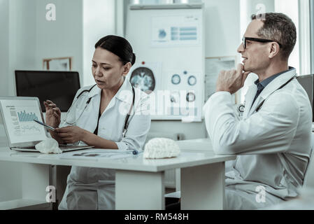 Scientifique médicale occupé pointant à l'écran avec des informations Banque D'Images