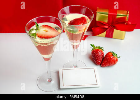 Deux verres de champagne avec des fraises et une carte vide entre eux avec un cadeau à l'arrière-plan . Concept de la Saint-Valentin Banque D'Images