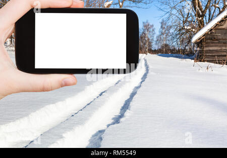 Travel Concept - photos touristiques de piste de ski de forêt dans petit village en hiver ensoleillée journée dans la région de Smolensk sur smartphone Avec cut Banque D'Images