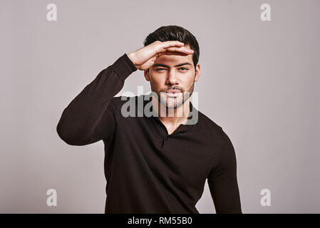 Closeup portrait de jeune homme sérieux, curieux de loucher sur la tête, sur le devant, à la recherche de quelque chose, pour l'avenir à huis clos, isolé sur fond blanc. Signer, symboles Banque D'Images