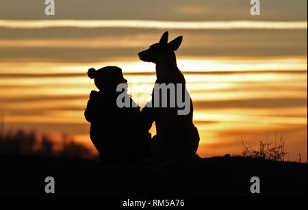 Toucher une photo d'un petit garçon et un chien de la race Berger Belge Malinois sur l'arrière-plan d'un beau coucher du soleil Banque D'Images