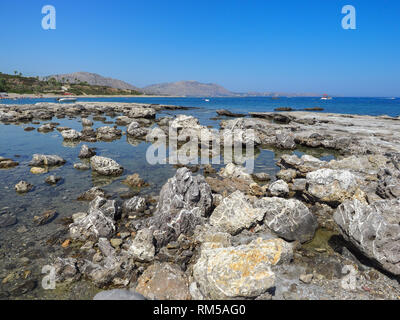 La beauté magnifique plage sauvage avec stony côte rocheuse, l'eau de mer peu profonde. De beaux paysages et journée ensoleillée sur Kiotari, Rhodes Island, Grèce. Banque D'Images