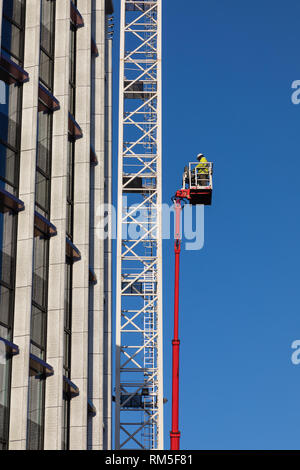 Birmingham, West Midlands / UK - 22 janvier 2019 : ouvrier en casque blanc et veste jaune sur une plate-forme élévatrice de rouge à pleine mesure. Banque D'Images