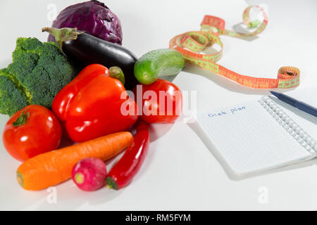 Les légumes frais, ruban à mesurer et ordinateur portable avec le plan de régime isolé sur fond blanc. La publicité d'aliments sains Banque D'Images